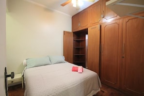 A bedroom with a bed, a nightstand, a wardrobe, and a ceiling fan.