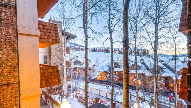 Une vue depuis un balcon donnant sur un village enneigé, avec ses bâtiments et ses arbres sans feuilles.