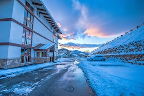 Une rue résidentielle où le sol, les maisons et une voiture garée sont recouverts de neige.