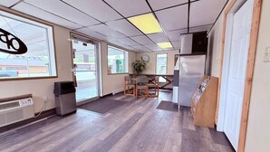 Une pièce spacieuse avec une grande fenêtre, une table en bois et un réfrigérateur blanc.
