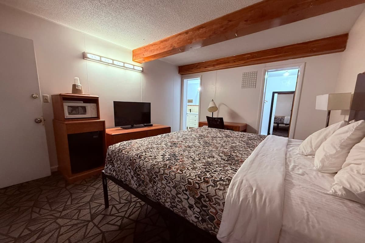 Een hotelkamer met een bed, een bureau met een televisie, een magnetron en een lamp.