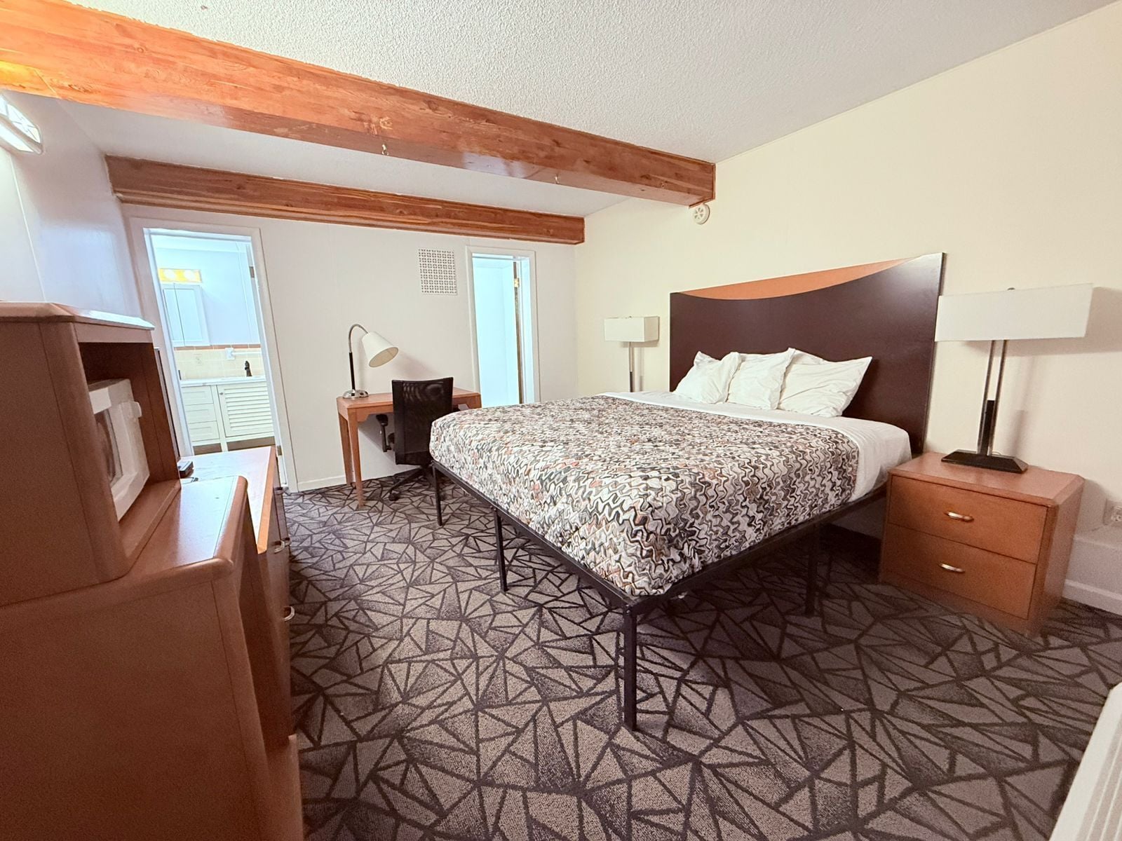 Una habitación de hotel con una cama, mesitas de noche, un escritorio y una silla.