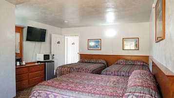 Une chambre avec deux lits, une commode, une télévision et un four à micro-ondes.