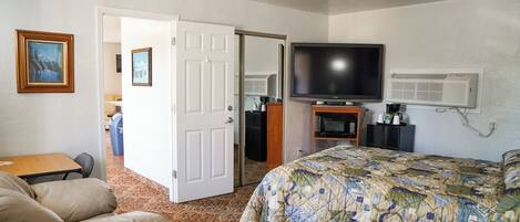 Una habitación de hotel con cama, televisor, aire acondicionado, escritorio y silla.