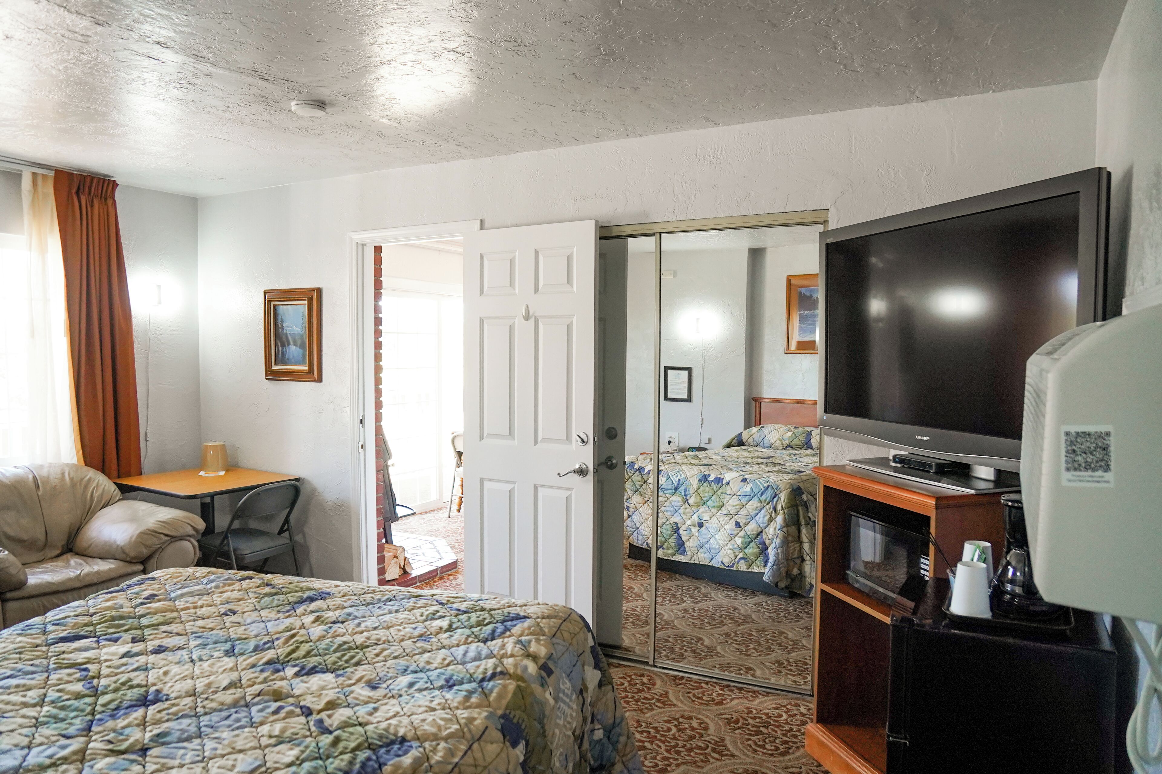 A hotel room with a bed, a TV, a coffee maker, and a mirror.