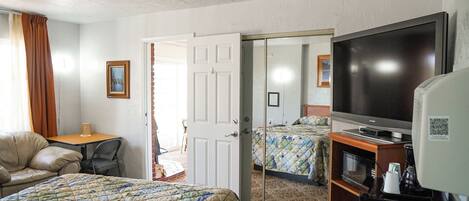A hotel room with a bed, a TV, a coffee maker, and a mirror.