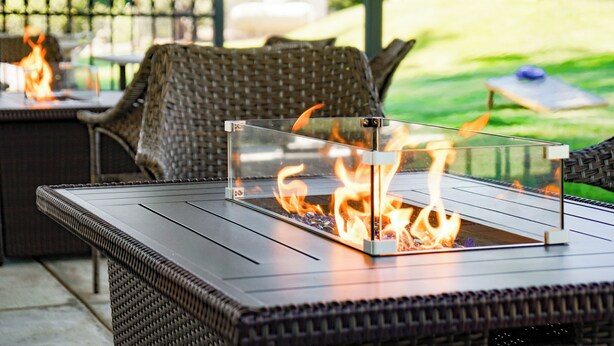 Un área de patio con una mesa de vidrio y una chimenea.