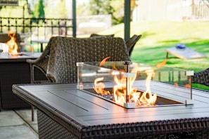 A patio area with a glass-top table and a fire feature. - Swiss Holiday Lodge (Mount Shasta)