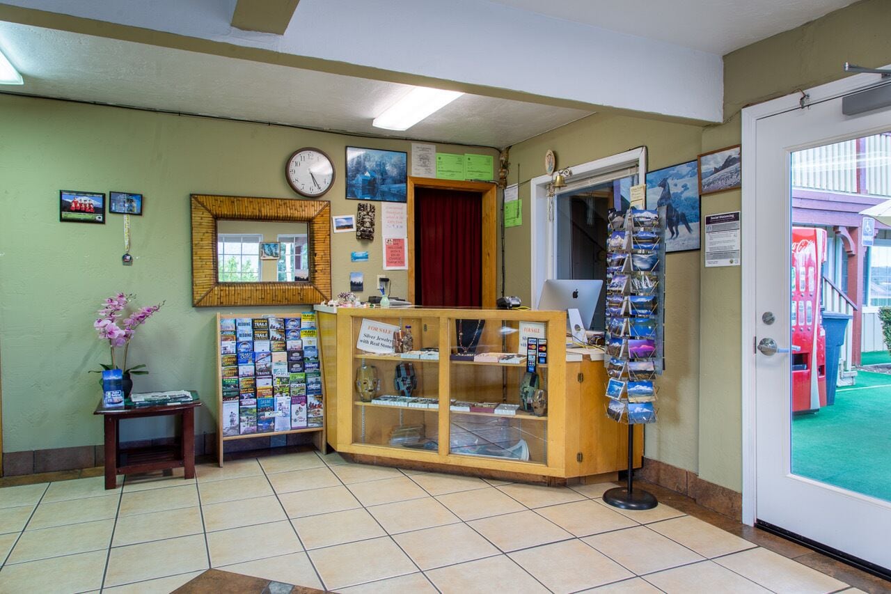 A reception area with a wooden counter, a clock, framed pictures, and a display of postcards.