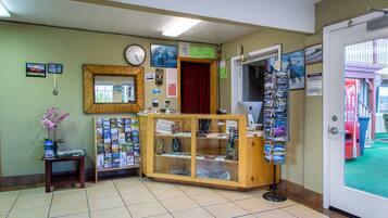 A reception area with a wooden counter, a clock, framed pictures, and a display of postcards.