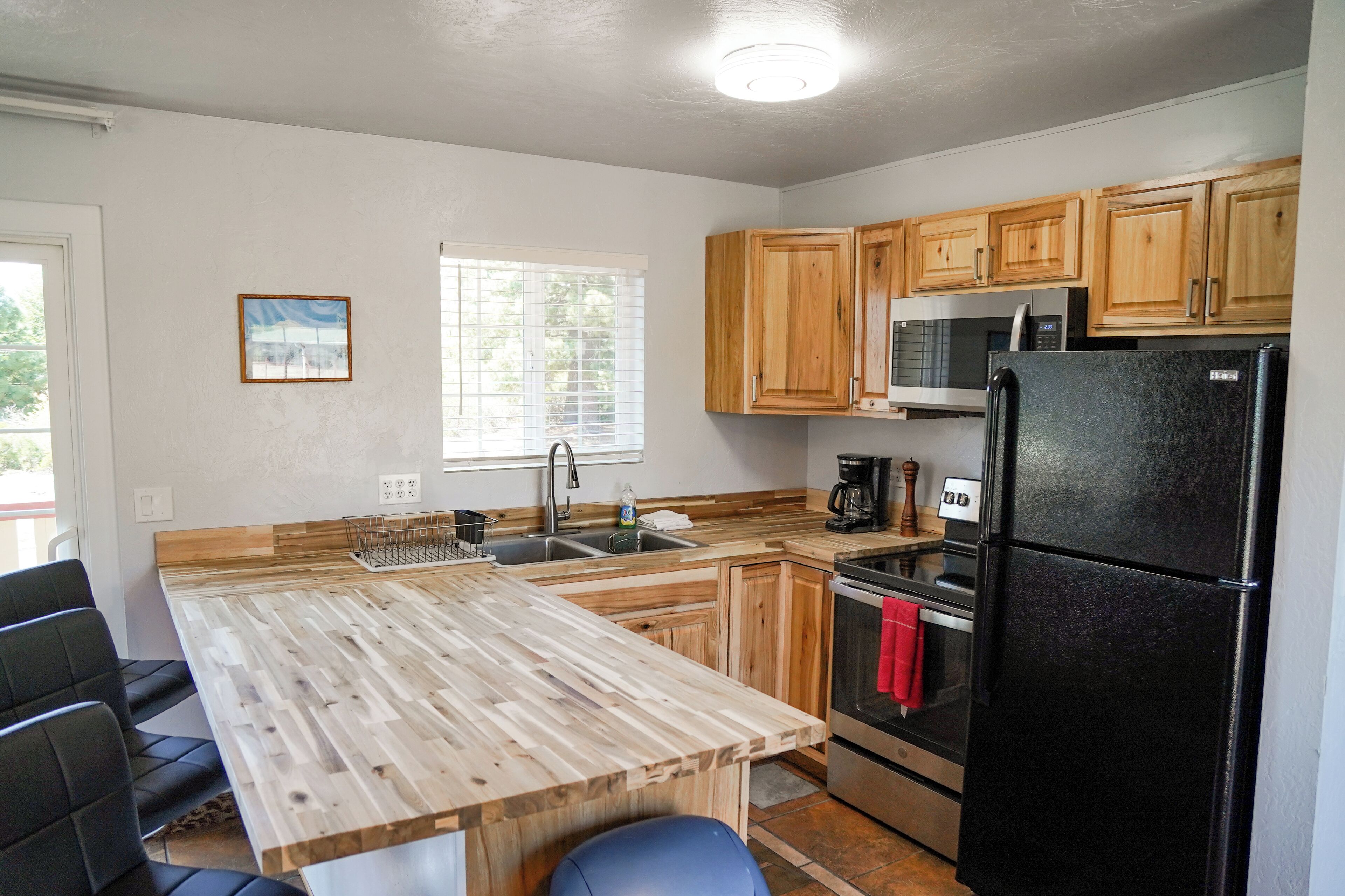A kitchen with wooden cabinets, a black refrigerator, a microwave, and a sink.