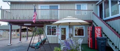 Ein Motel mit überdachter Veranda, Schaukelstühlen und Topfpflanzen.