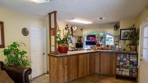 Una sala de estar acogedora con una mesa de centro de madera, un sofá de cuero marrón y varias plantas.