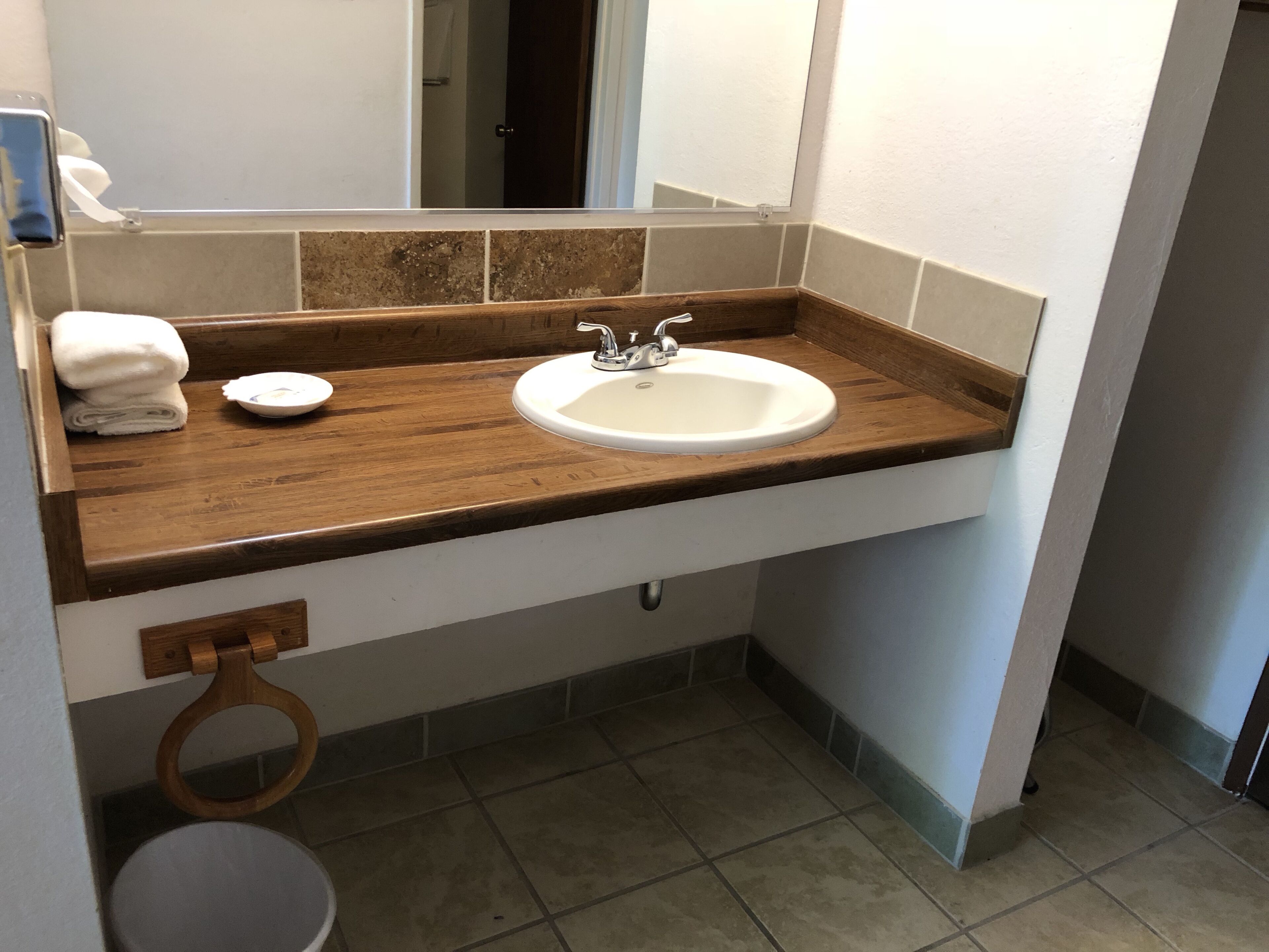 A bathroom with a wooden countertop, a white sink, and a mirror.