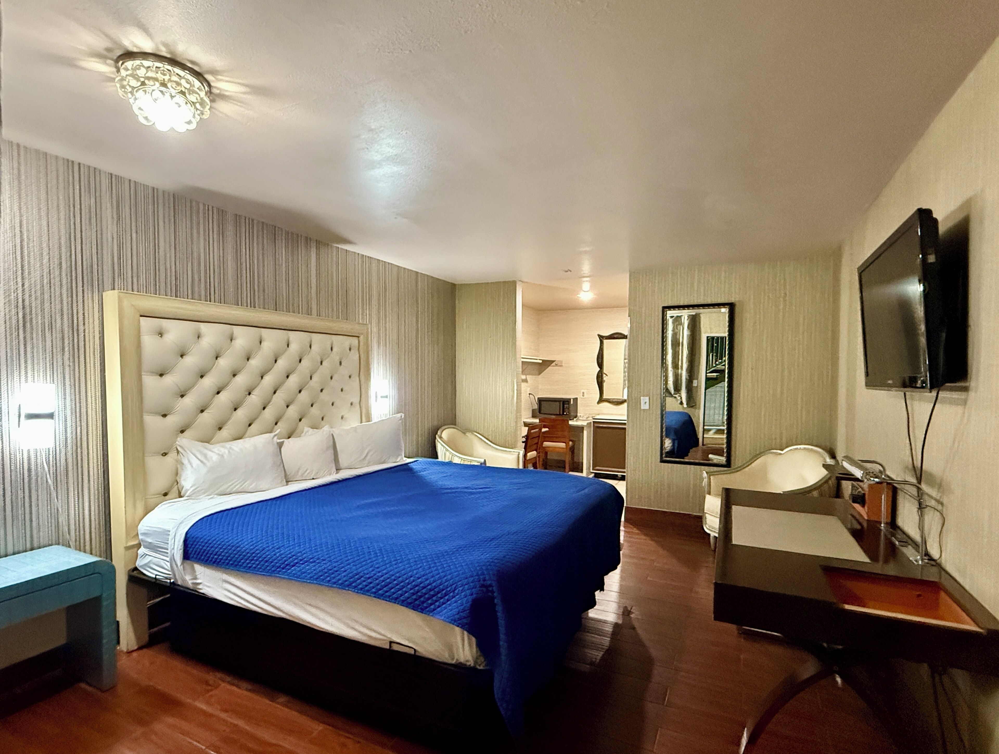 Una habitación de hotel con una cama grande, un escritorio, una silla, un televisor y un espejo.