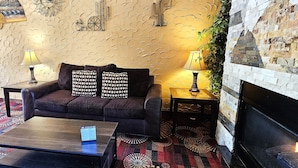 Ein gemütliches Wohnzimmer mit einer Couch, zwei Lampen, einem Kamin und einem gemusterten Teppich.