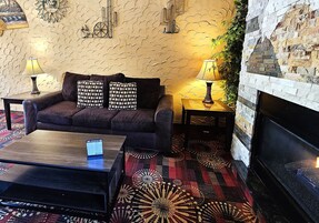Una sala de estar acogedora con un sofá, dos lámparas, una chimenea y una alfombra estampada.
