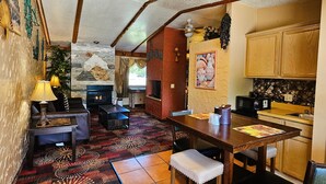 Ein gemütliches Interieur mit Kamin, gemustertem Teppich, Holzmöbeln und einer Küchenzeile.