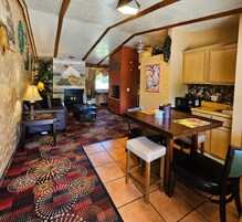 Un interior acogedor con chimenea, alfombra estampada, muebles de madera y una zona de cocina.