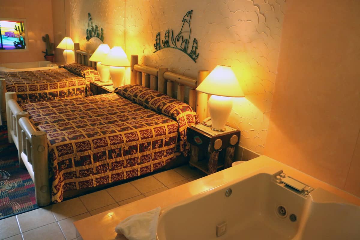 Une chambre d’hôtel avec deux lits, une baignoire et des œuvres d’art murales.