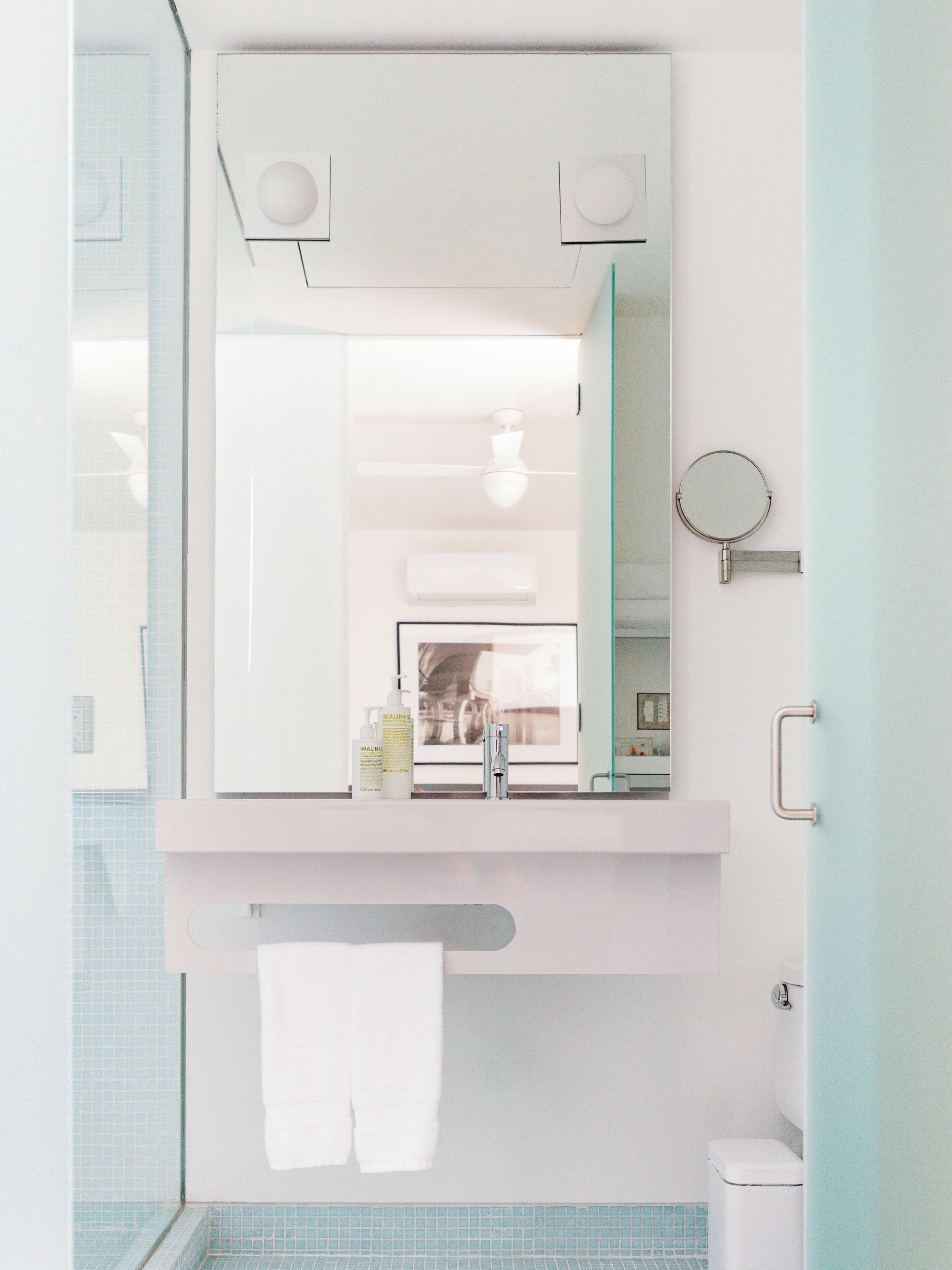 A bathroom with a mirror, sink, towel rack, and a toilet.