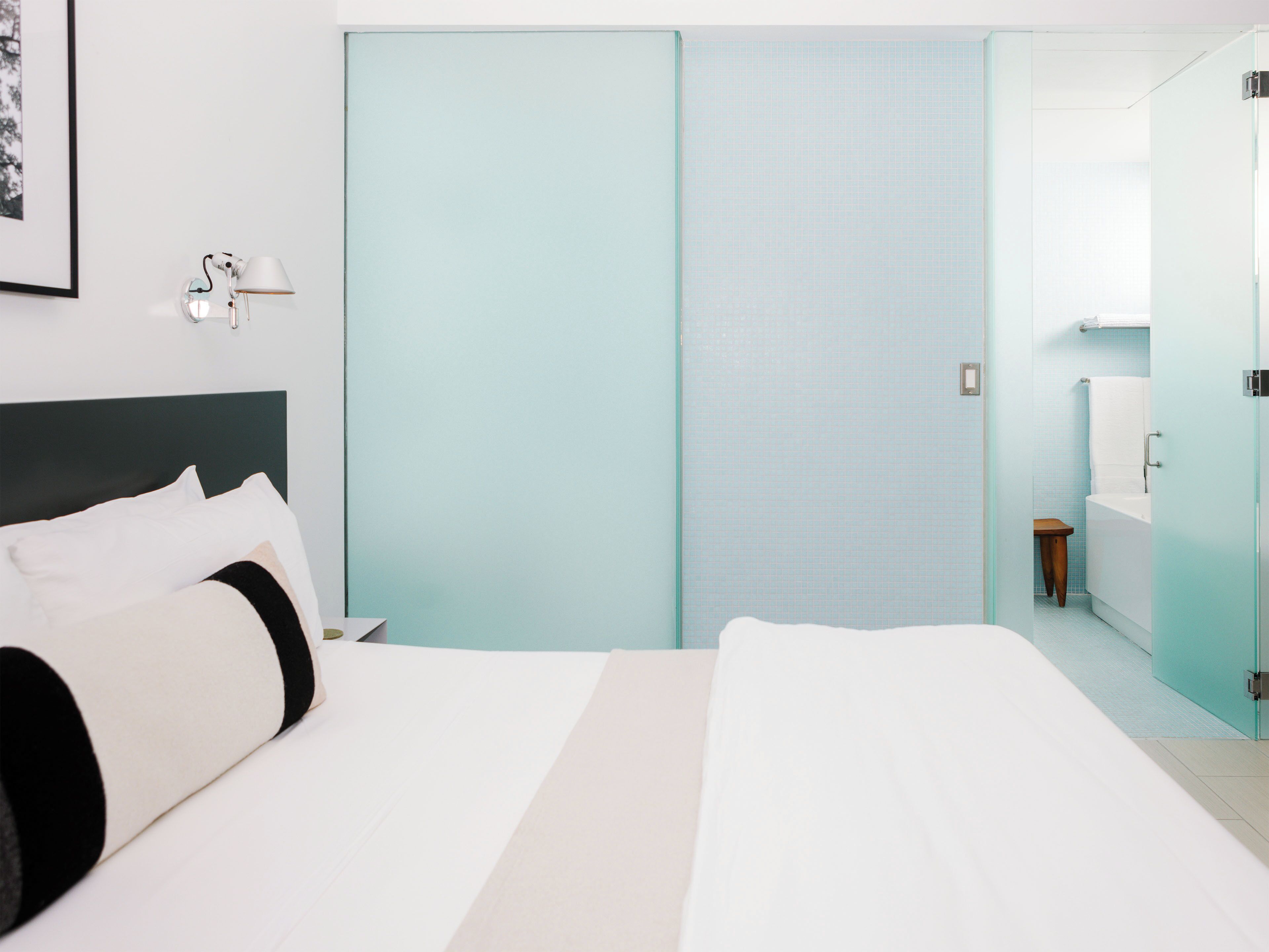 Ein Hotelzimmer mit Bett, Nachttisch, Lampe, Badezimmer mit Badewanne und Toilette.