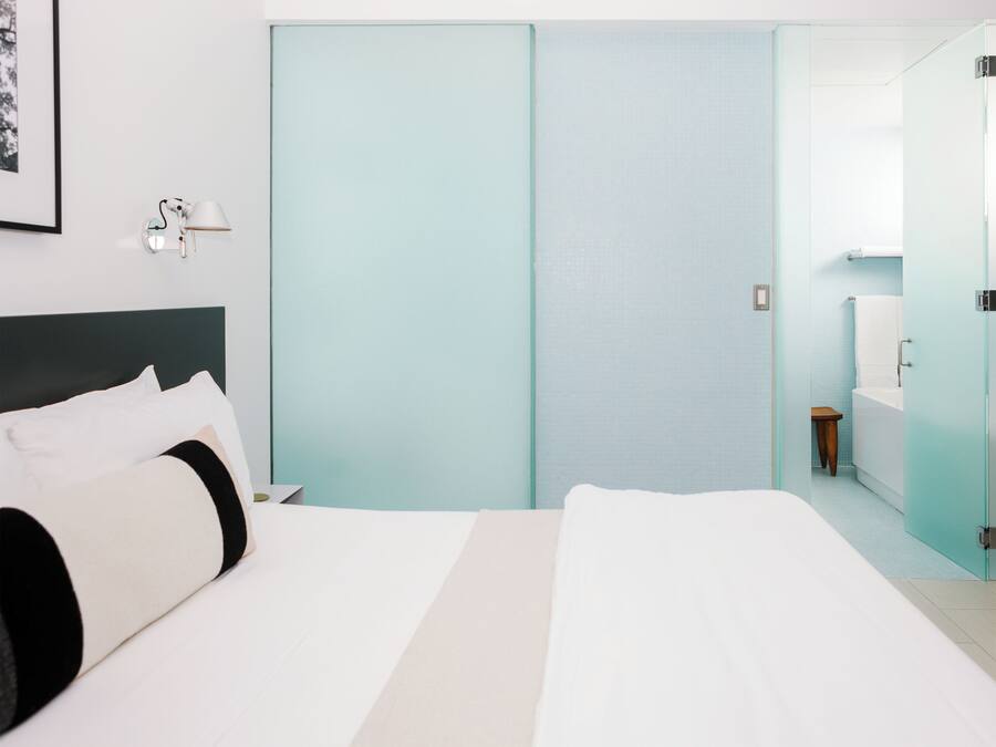 Une chambre d’hôtel comprenant un lit, une table de chevet, une lampe, une salle de bain avec une baignoire et des toilettes.