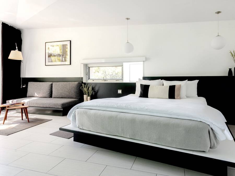 A modern bedroom with a large bed, a sofa, and a window.