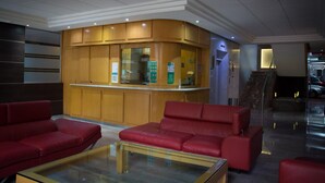 Un hall d’entrée avec un comptoir de réception, des canapés en cuir rouge et une table basse en verre.