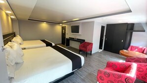 Une chambre d’hôtel avec deux lits, un bureau, une télévision et des chaises à motifs rouges.