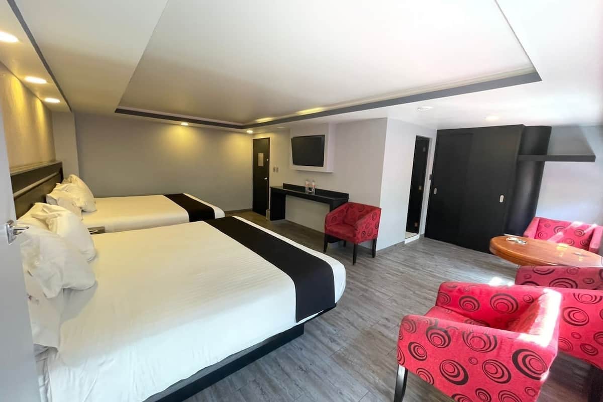 Habitación de hotel con dos camas, un escritorio, un televisor y sillas rojas con estampado.