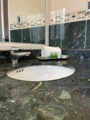 A bathroom with a marble sink, a mirror, and a towel rack.