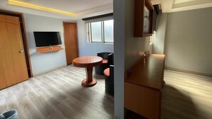 Un salon moderne avec un téléviseur à écran plat, une table ronde en bois et un canapé.