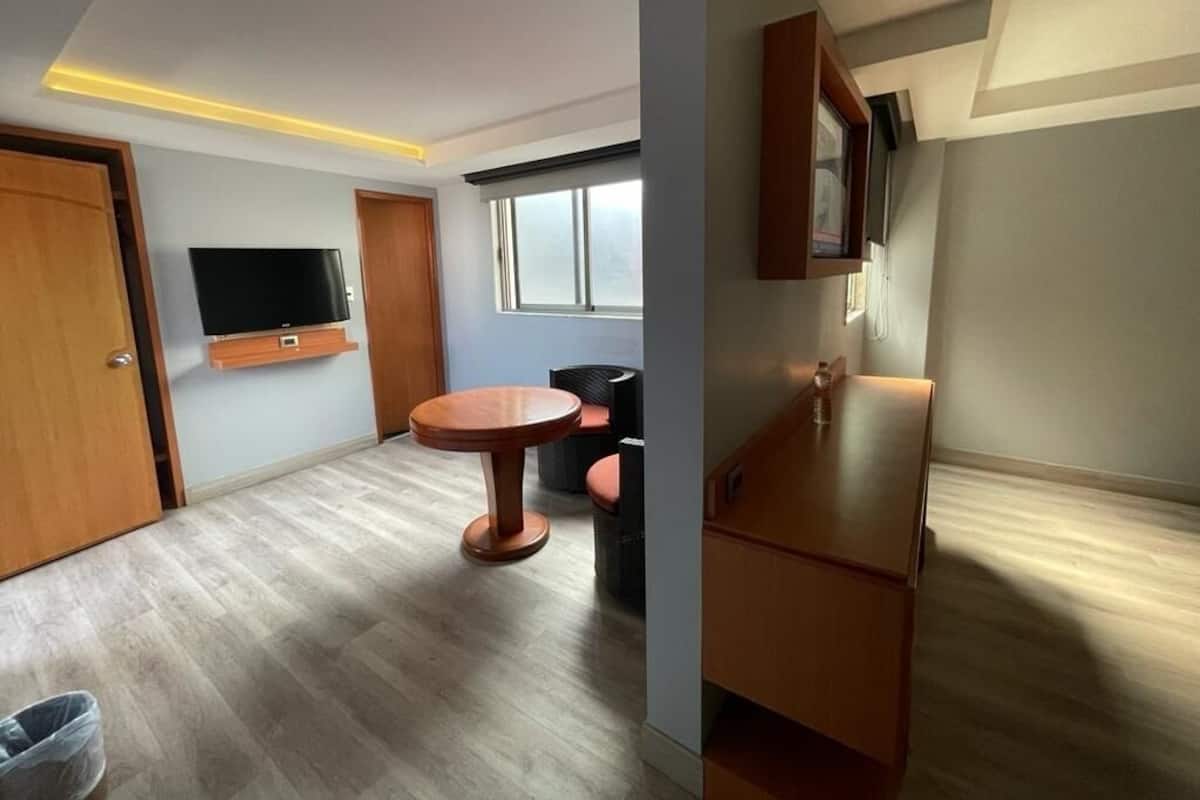 Una sala de estar moderna con un televisor de pantalla plana, una mesa redonda de madera y un sofá.