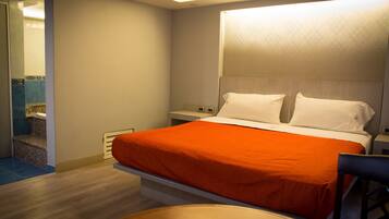 A hotel room with a bed, bedside tables, and a small seating area.