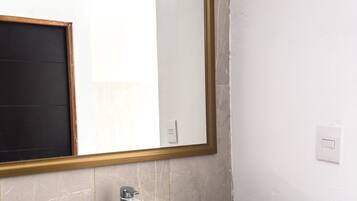 A bathroom with a large mirror, a sink, and a light switch on the wall.