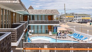 A hotel with a pool area, outdoor seating, and a view of the street. - Charlroy Motel (Seaside Park)