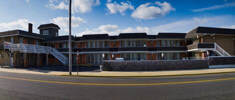 Un motel con una escalera central, varias habitaciones y un estacionamiento.