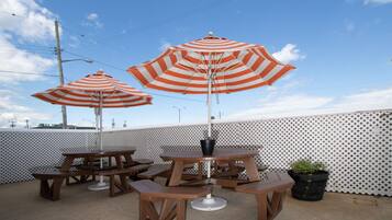 A patio area with picnic tables and striped umbrellas.