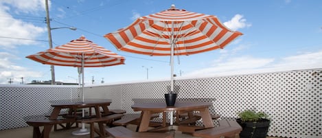 Un patio con mesas de picnic y sombrillas a rayas.