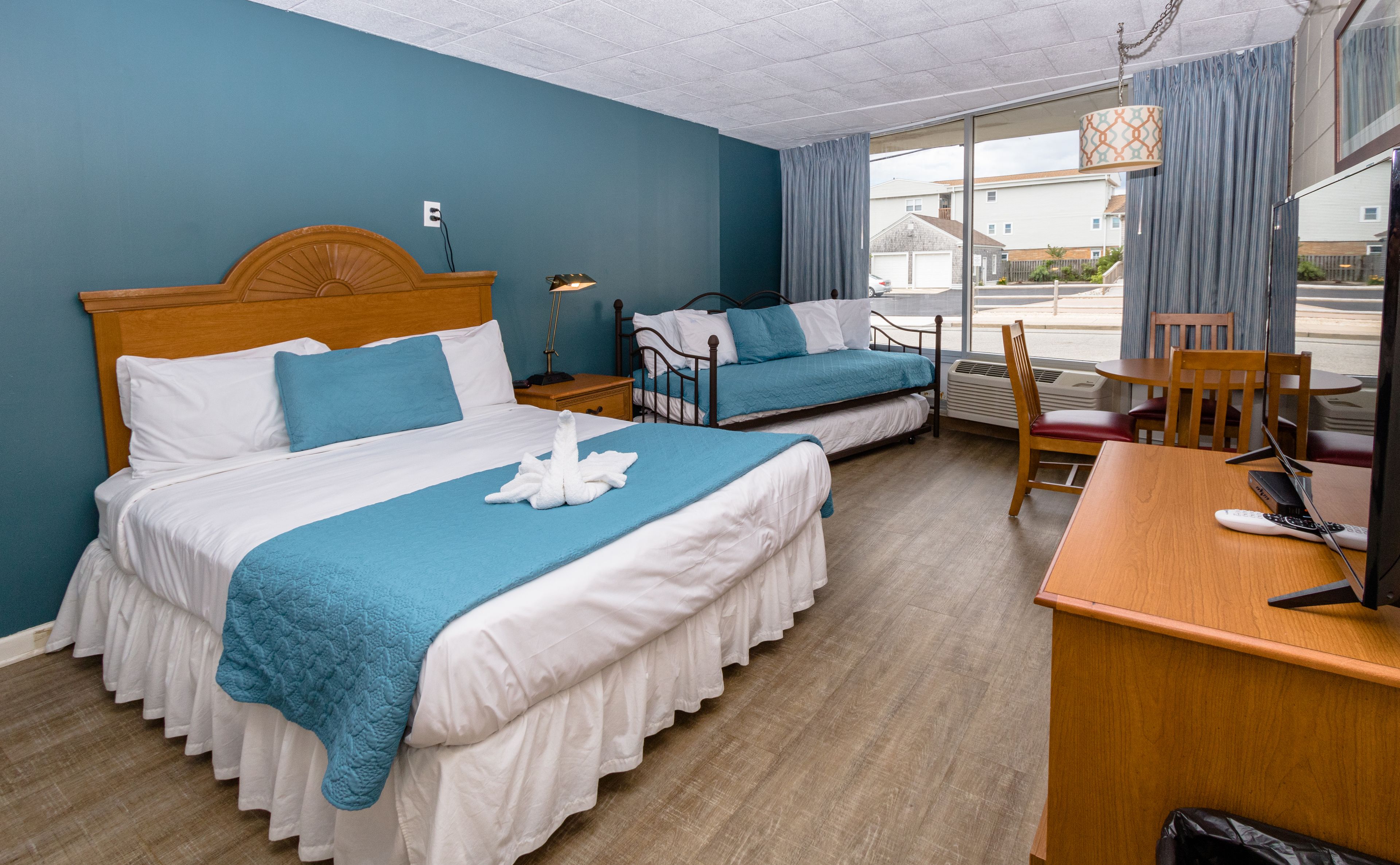 A hotel room with two beds, a desk, and a chair.