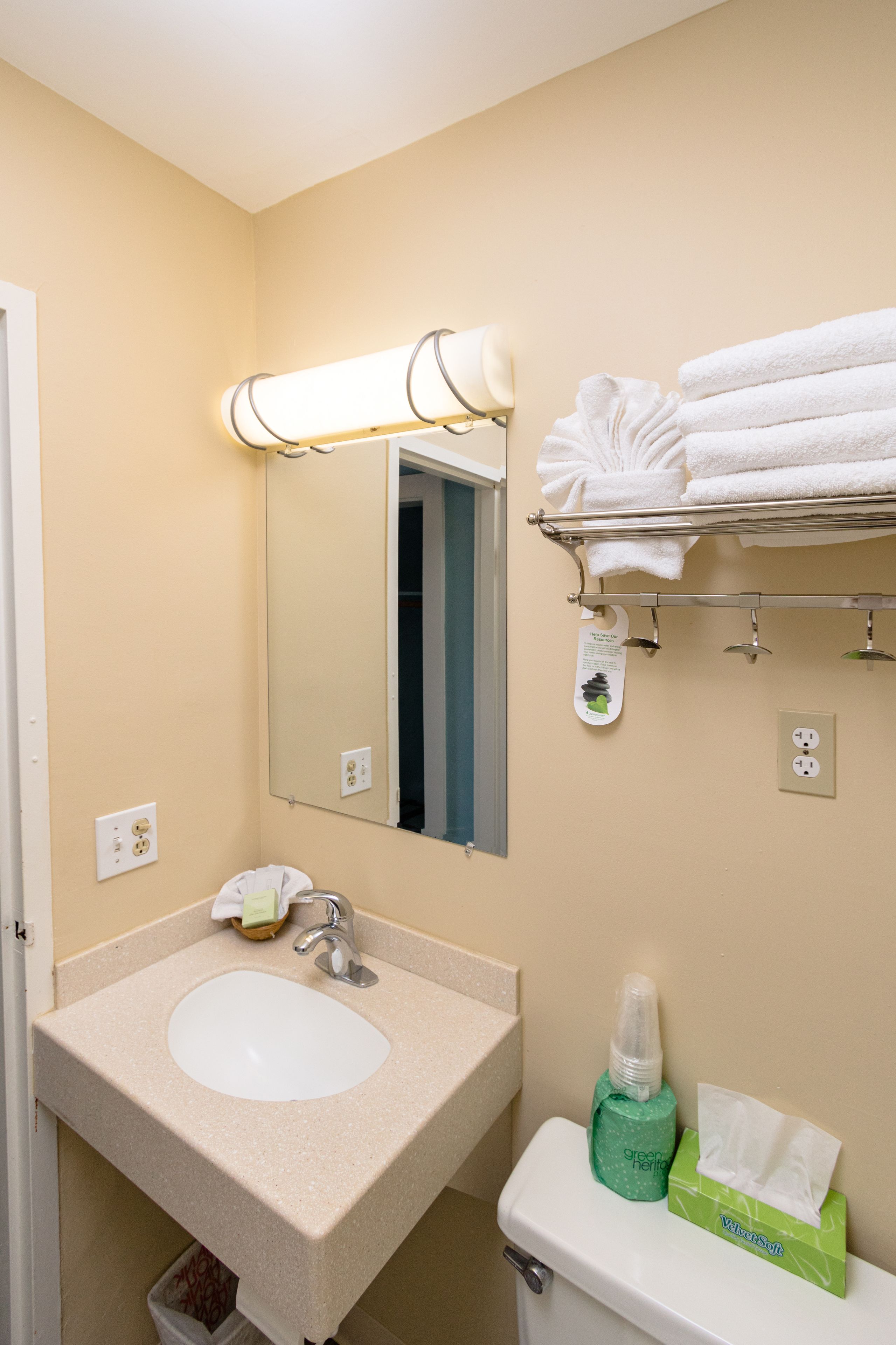 A bathroom with a sink, mirror, towel rack, and toiletries.