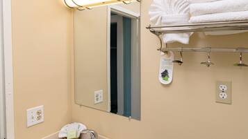 A bathroom with a sink, mirror, towel rack, and toiletries.