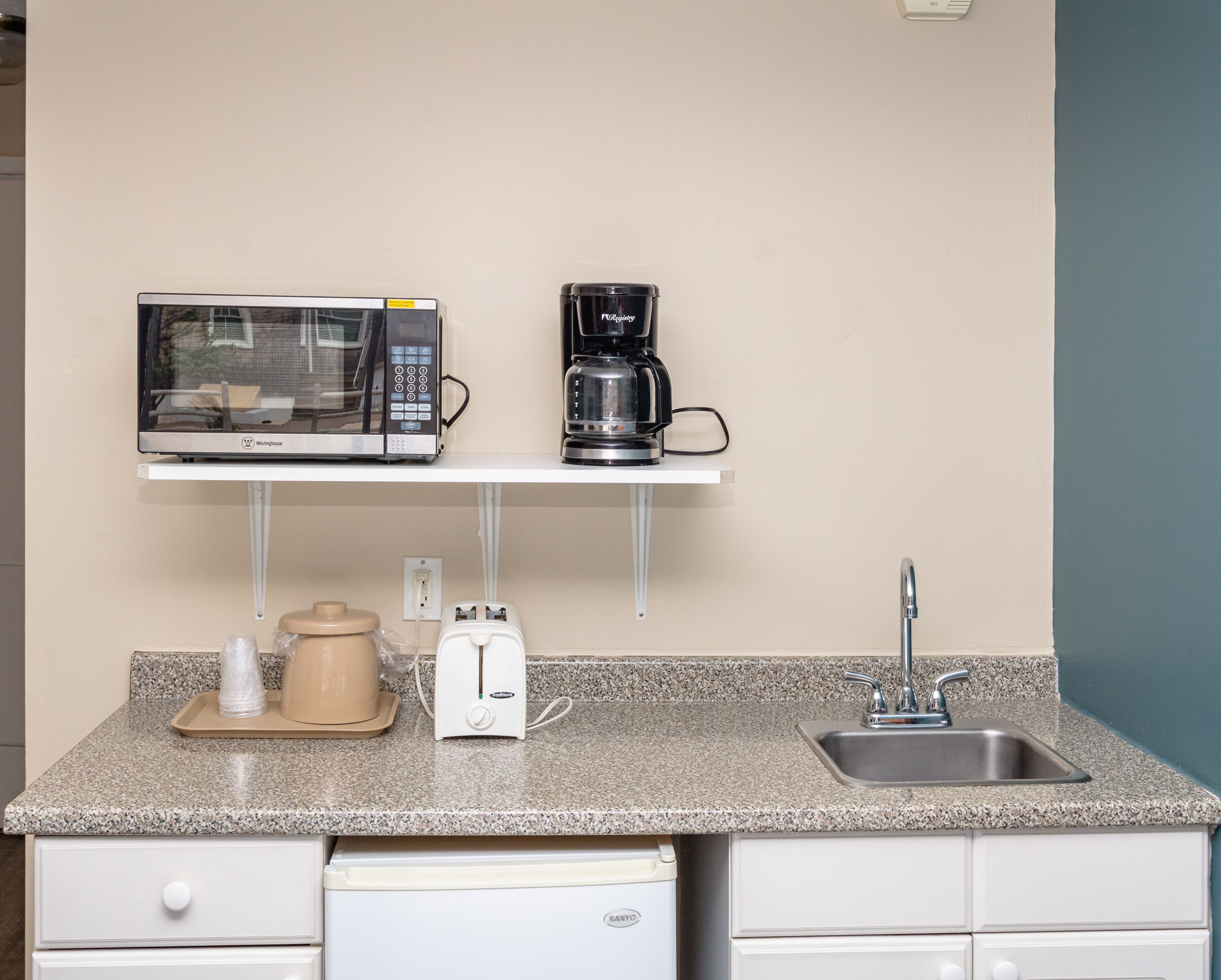 Una kitchenette equipada con microondas, cafetera, tostadora y lavamanos.