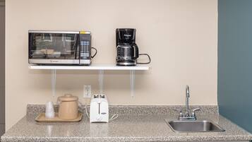 Una kitchenette equipada con microondas, cafetera, tostadora y lavamanos.