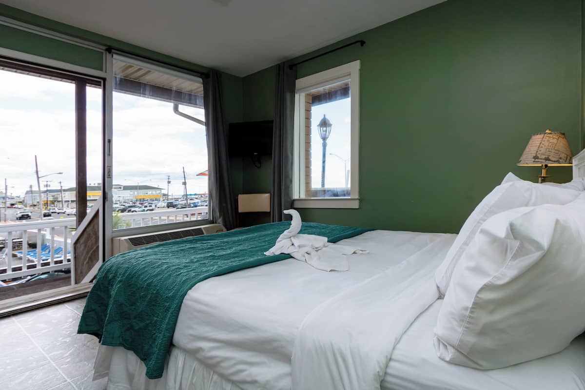 A hotel room with a bed, a window with a view of a cityscape, and a lamp on the nightstand.