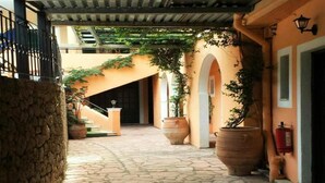 A stone-paved courtyard with arches, large planters, and a staircase leading to an upper level. - Arianna Studios And Apartments (Corfu)