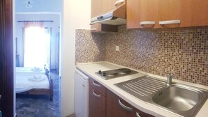 A compact kitchen with a sink, stove, and cabinets. - Arianna Studios And Apartments (Corfu)