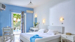 A bedroom with a large bed, a bedside table, a chair, a small table with a plant, and a window with curtains. - Noble Hotel Suites (Hersonissos)