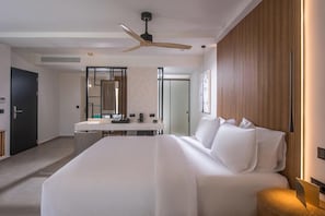 A hotel room with a bed, a desk with a chair, a mirror, and a ceiling fan. - Noble Hotel Suites (Hersonissos)